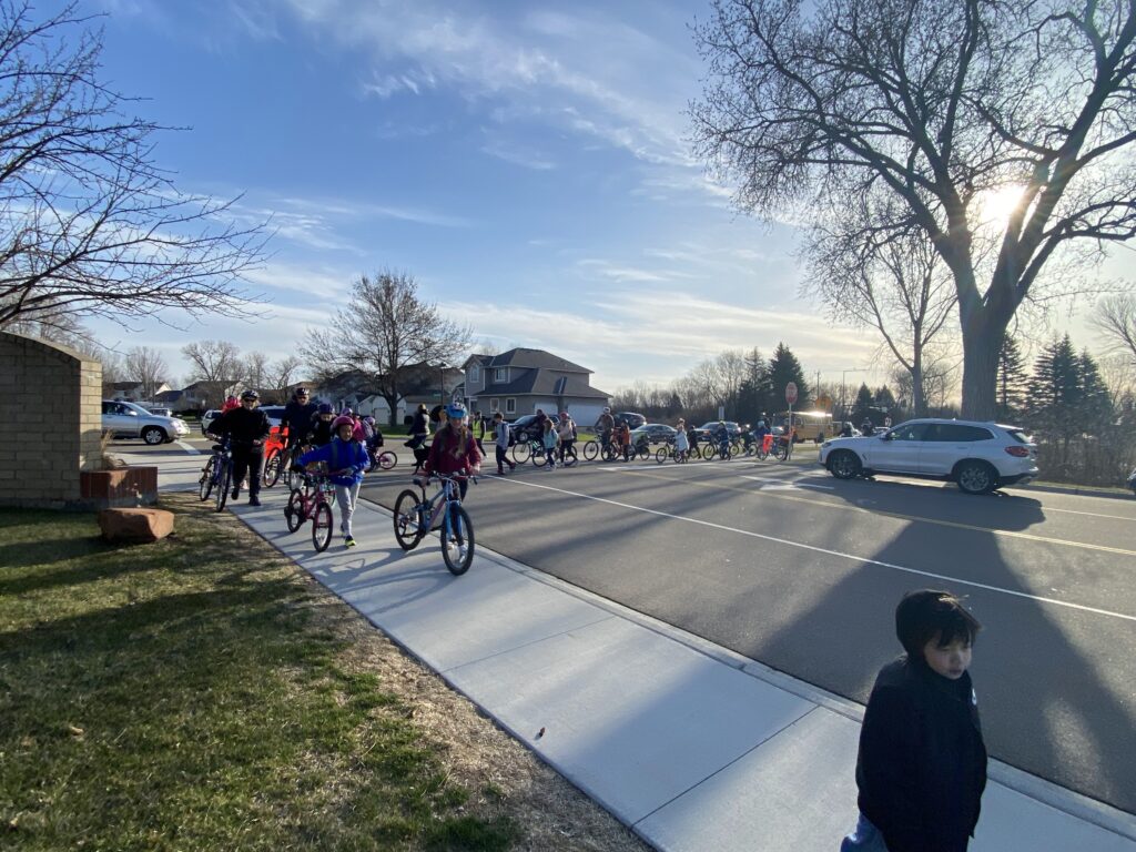 A beautiful sunny day is pictured with over twenty students and families biking and walking to school.