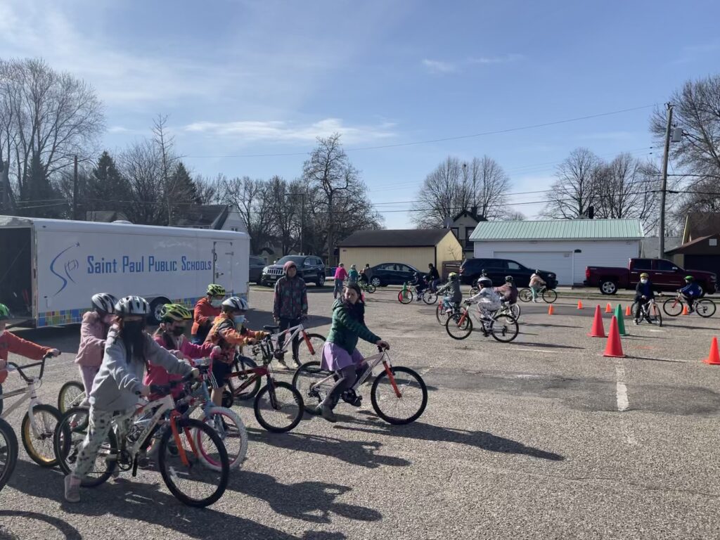 A group of students waits for instructions from BikeMN staff, Angela, before starting the bike-skills course in the parking lot of Lake Phalen Elementary school. 